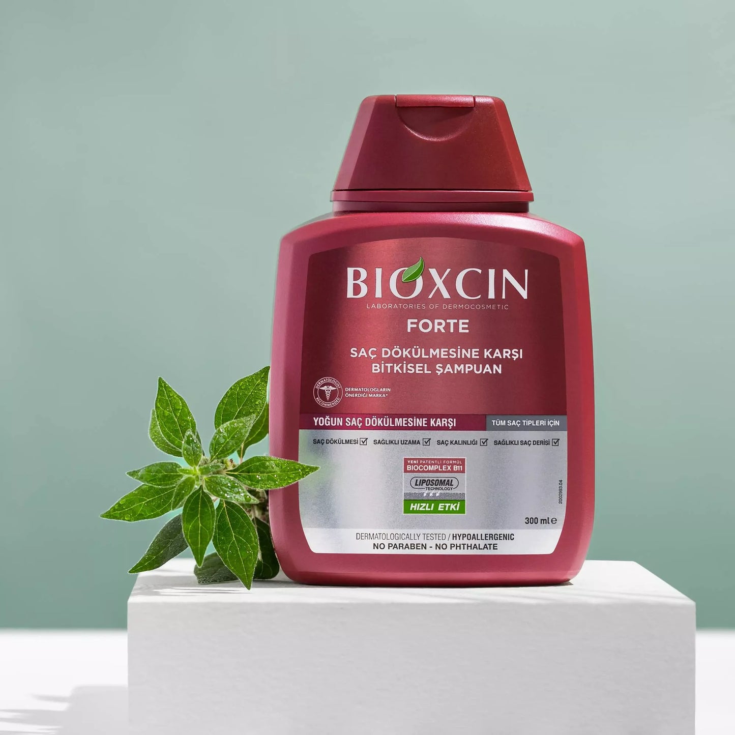 Bioxcin Forte shampoo bottle with green leaves on a light gray background