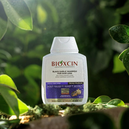 BIOXCIN black garlic shampoo bottle with green leaves in the background