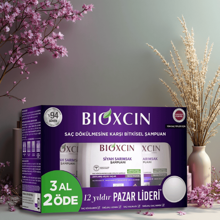 BIOXCIN black garlic shampoo triple pack packaging with decorative elements on a table.