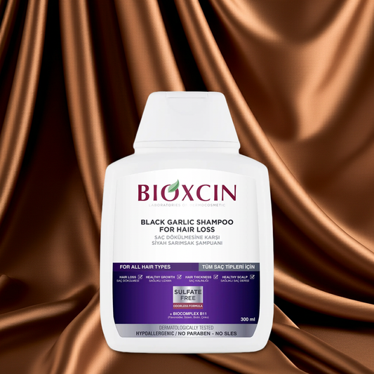 Bioxcin black garlic shampoo bottle on a brown satin background