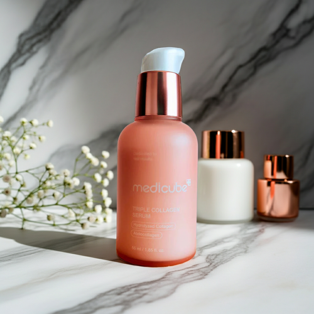 Medicube triple collagen serum skincare bottle on a marble surface with flowers and other bottles in the background