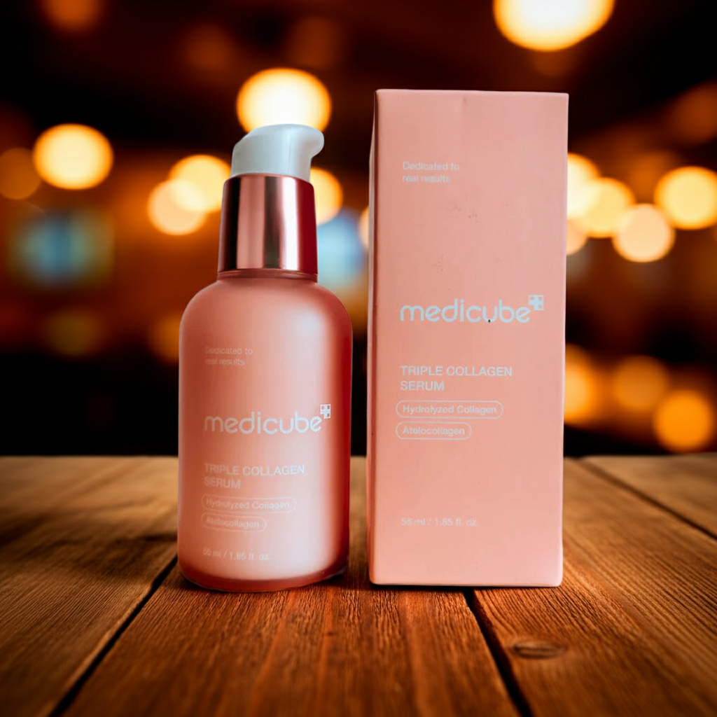 Medicube Triple Collagen Serum bottle and box on a wooden surface with blurred lights in the background
