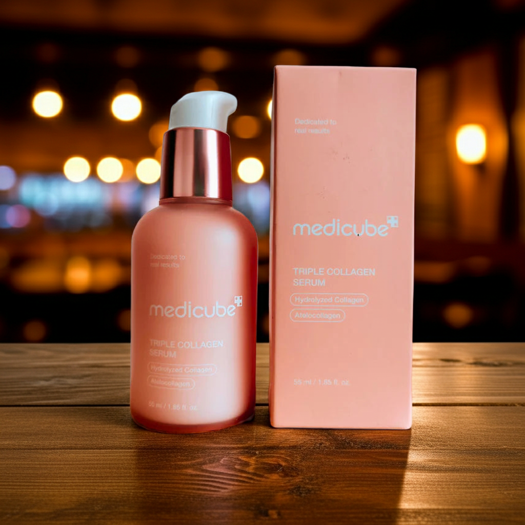 Medicube Triple Collagen Serum bottle and box on a wooden surface with blurred lights in the background